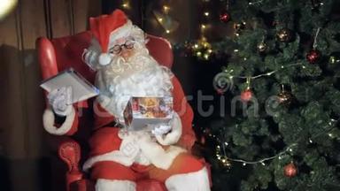圣诞老人坐在圣诞树附近的椅子上包装一个礼盒。